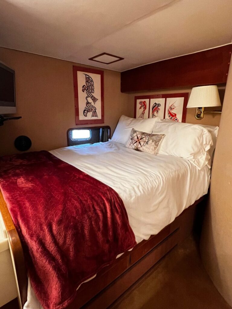 A bed with white sheets and red blanket.